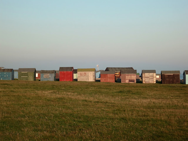 Row of huts at Portland Bill in Dorset. With small wind turbine like a star.
