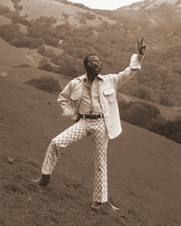 Curtis Mayfield giving peace sign on hillside