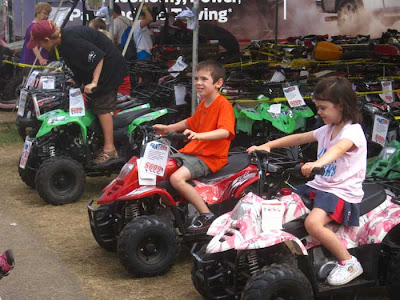 Two boys on red or green mini atvs, girl on a pink one