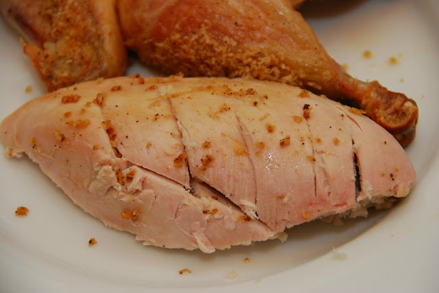 close up of roasted chicken breast  in front of a roasted chicken leg