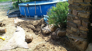 Starting to dig the trench, a very big stone is right in our way and the existing drainage pipe is visible