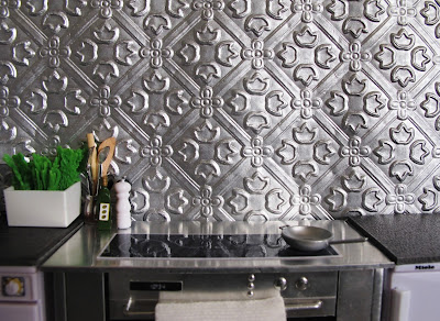 Modern dolls' house miniature kitchen with grey laminate bench and silver pressed-tin splash back.