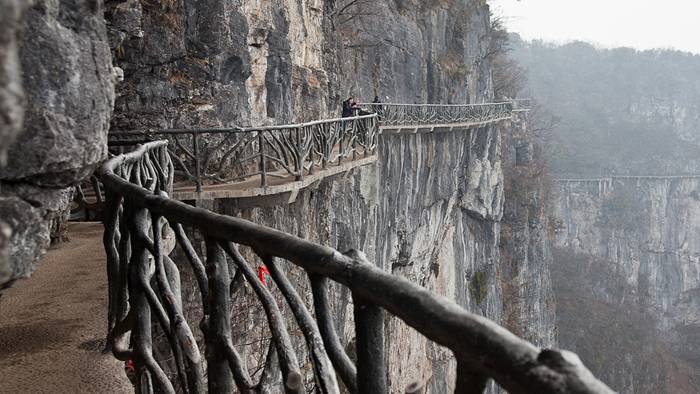 Skywalk On Tianmen Mountain — China Jutting out from a sheer cliff 1,430 meters high, the glass skywalk in Zhangjiajie National Forest Park offers sightseers terrifying thrills and clear view of the mountains below as they tread nervously across the 60 meter long bridge encircling the vertical cliffs of Tianmen Mountain in Hunan province. The 3ft-wide, 2.5in thick glass walkway is so scary that sightseers are requested to wear cloth slip-ons over their shoes when they cross the skywalk, presumably to make the job easier for the cleaners.