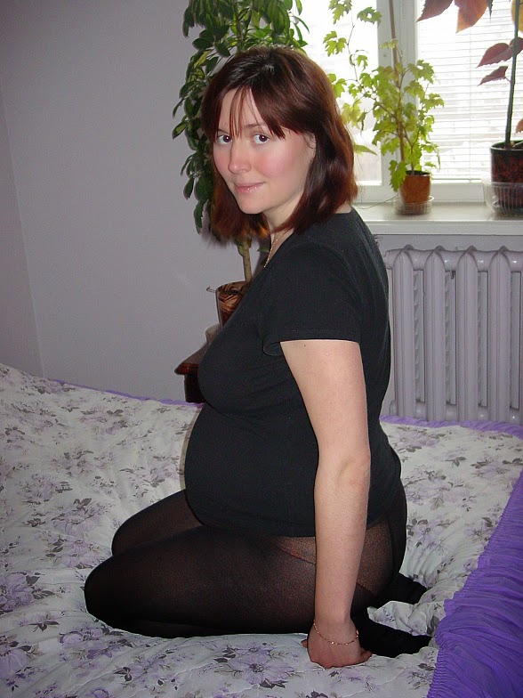 Зрелая беременная жена позирует в кресле