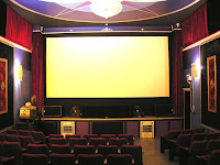 image Kawartha Lakes Highlands Cinema Kinmount Interior of one theatre showing large screen, in art deco surroundings from a ceiling medallion to long burgundy drapes.