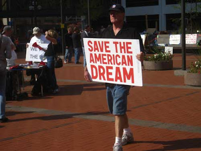 Man walking with sign reading Save the American Dream