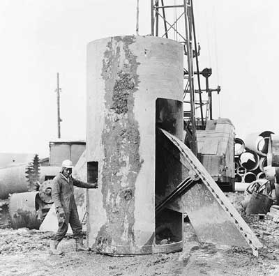 The bell is formed at the bottom of the caisson shaft by a belling bucket with retractable cutters. The example shown here is for an 8-foot- (2.44-m)-diameter shaft and makes a bell 21 feet (6.40 m) in diameter. The bell is formed at the bottom of the caisson shaft by a belling bucket with retractable cutters. The example shown here is for an 8-foot- (2.44-m)-diameter shaft and makes a bell 21 feet (6.40 m) in diameter.