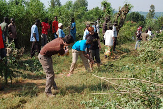 Jordan swings a machete clearing brush for a new road as we assisted the community during Umuganda.