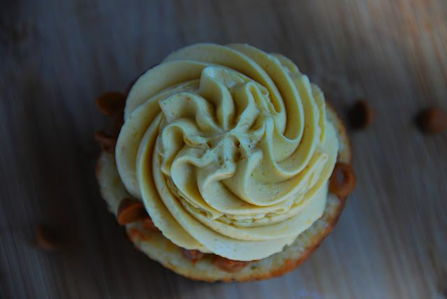 overhead close up of cupcake in brown wrapper with swirl of white icing on top