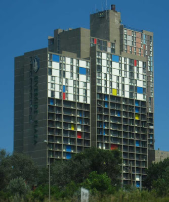 Riverside Plaza in Minneapolis with most of the panels painted white, blue, yellow and red, some in the background in dark peachy tan