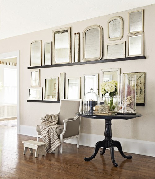 different shapes and sized mirrors on floating shelves mounted on a wall as art in a hallway