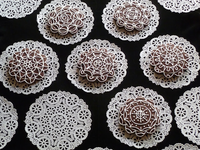 paper doiles on black with custom decorated dark-chocolate tea biscuits
