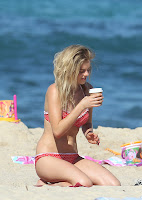 Samara Weaving in a bikini on the beach grabbing a drink