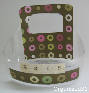 close up of plastic repurposed basket with green and pink decorative paper and stickers spelling out "keys"