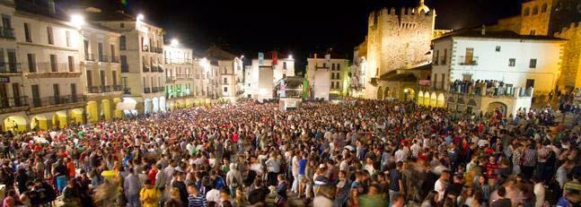 panorámica nocturna de la ciudad de Caceres con miles de personas celebrando el Womad