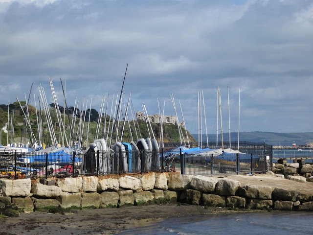 Boats stored on land with small beach in foreground and castle beyond