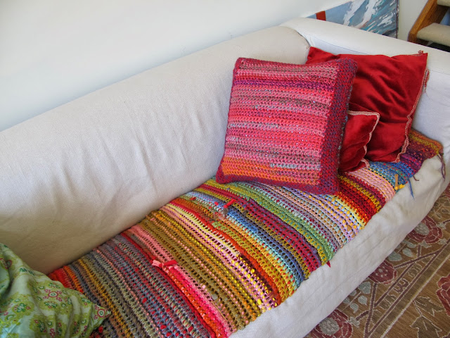 a couch covered in a t-shirt yarn crochet blanket