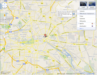 Ein Screenshot zeigt eine Karte in Google Maps. Oben rechts in der Ecke sind die Buttons "Karte" und Fotos" und ein Drop Down zur Auswahl verschiedener Ansichten und hat "Öffentliche Verkehrsmittel" ausgewählt.