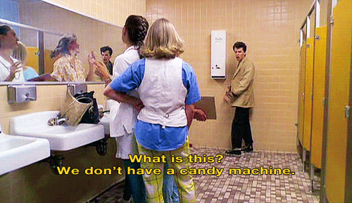 Animated gif of a teenage boy in a girl's bathroom pointing to the tampon dispenser and angrily demanding, "What is this? We don't have a candy machine!"