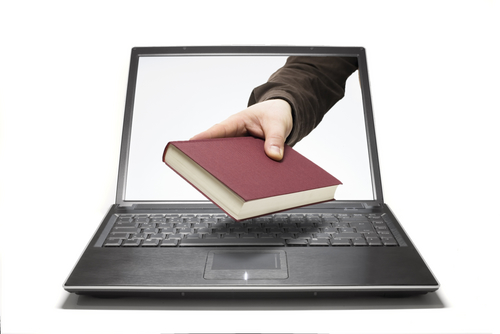 hand reaching through a laptop offering a book