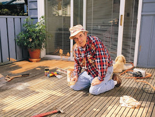 Homeowner laboring on refinishing wood deck