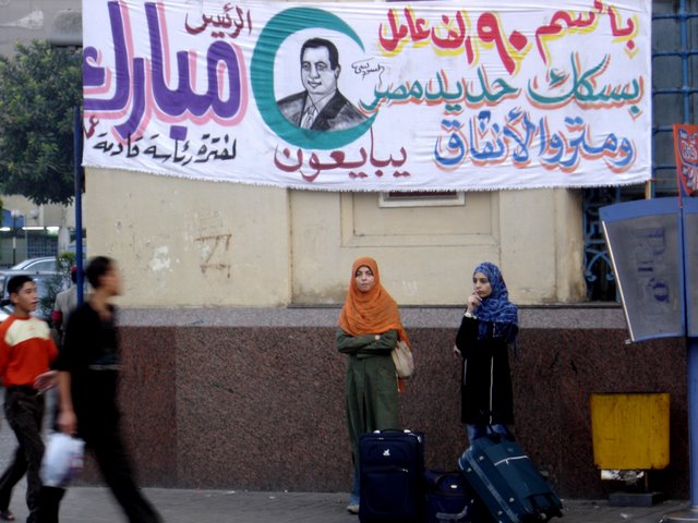 Niñas jovenes bajo  pancarta de Hosni  Mubarak.