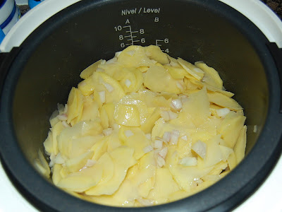 La patata con la cebolla y el aceite en la cubeta
