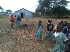 Masi children playing outside there school house.