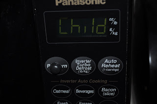 Microwave screen saying the world Child on it, under the screen you can see another sticky button on the popcorn button
