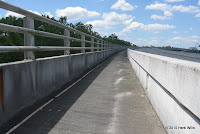 On the bridge on the Biker/Hiker lane. The wall and rail on the left separates you from the drop into the river, and the wall on the right separates you from auto traffic.