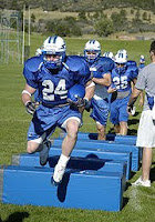 Air Force football players practice by running over pads.