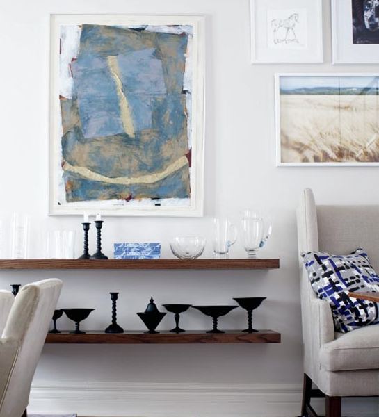 Floating shelves and a wall full of art in a small dining room in a cottage