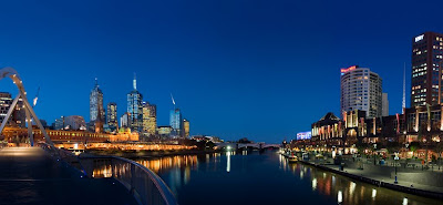 Foto de dentro do Rio Yarra retrata as edificações das margens no crepúsculo.