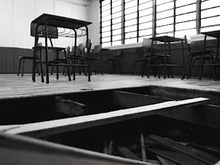Uma sala de aula vazia e com o piso em pedaços