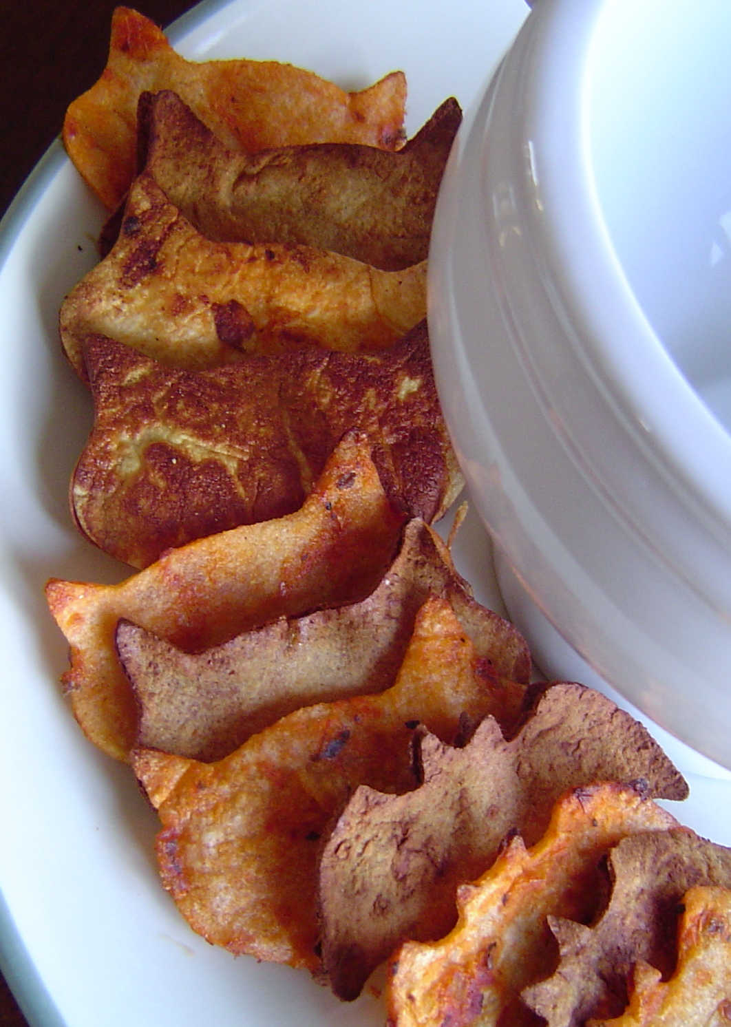 cat and bat shaped homemade tortilla chips lined up on a plate