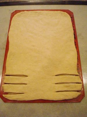bread dough flattened out on a liner with a few 1-inch pieces cut along the side