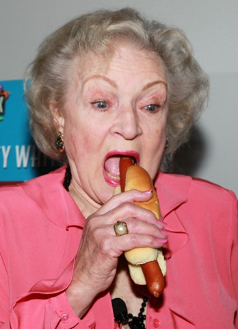 Betty White eating a tubesteak without ketchup or mustard.