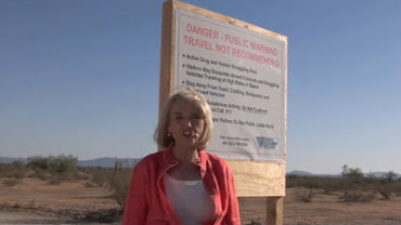 Arizona Gov. Jan Brewer is shown next to a warning sign in the desert - 80 Miles inside AZ.