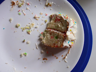 Single slice of confetti cake on a blue plate surrounded by crumbs