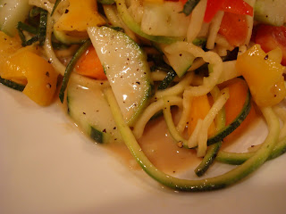 Zucchini noodles with vegetables and peanut sauce on white plate showing pooling of dressing
