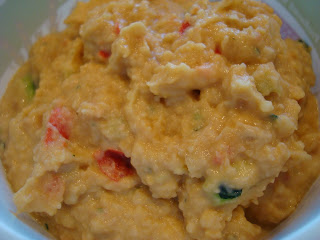 Hummus in bowl showing hints of red pepper and zucchini