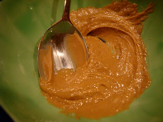 Mixed up peanut butter and nutritional yeast in green bowl with spoon