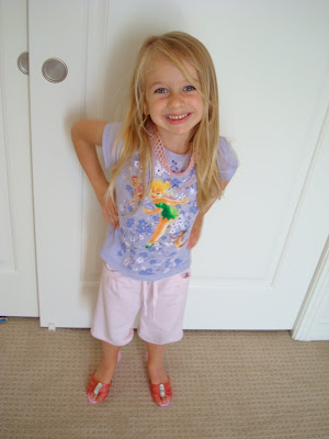 Young girl in pink high heels with hands on hip standing in front of door smiling 