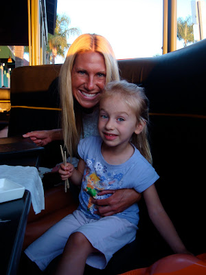 Woman and child sitting in booth hugging and holding chopsticks