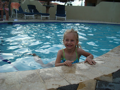 Young girl swimming in pool holding onto side edge