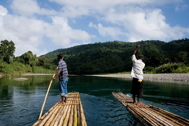 photo showing two raft captains rowing down the rio grande with mountains in background