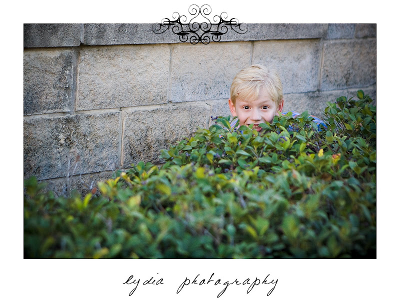 Little boy hidding behind some bushes at lifestyle kids portraits in San Antonio, Texas