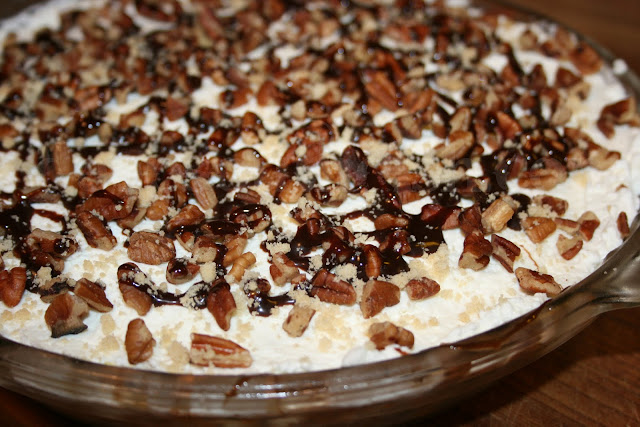 Banana Cream Cheese Pie with Shortbread Cookie Crust Banana slices, layered in a cream cheese filling on a shortbread pie crust, covered in whipped topping, chopped pecans and chocolate sauce.