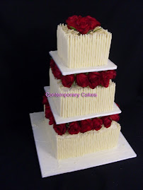 3 tier square stacked cake with white chocolate cigarellos with fresh red roses.