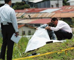 Police detectives observe the body of a murder victim that was found near the Tobias Bolanos Airport in San Jose, Costa Rica, August 20, 2008. Costa Rican authorities are trying to determine if four recent murder cases were commited by the same person. (Photo: Francisco Rodriguez/La Nacion)